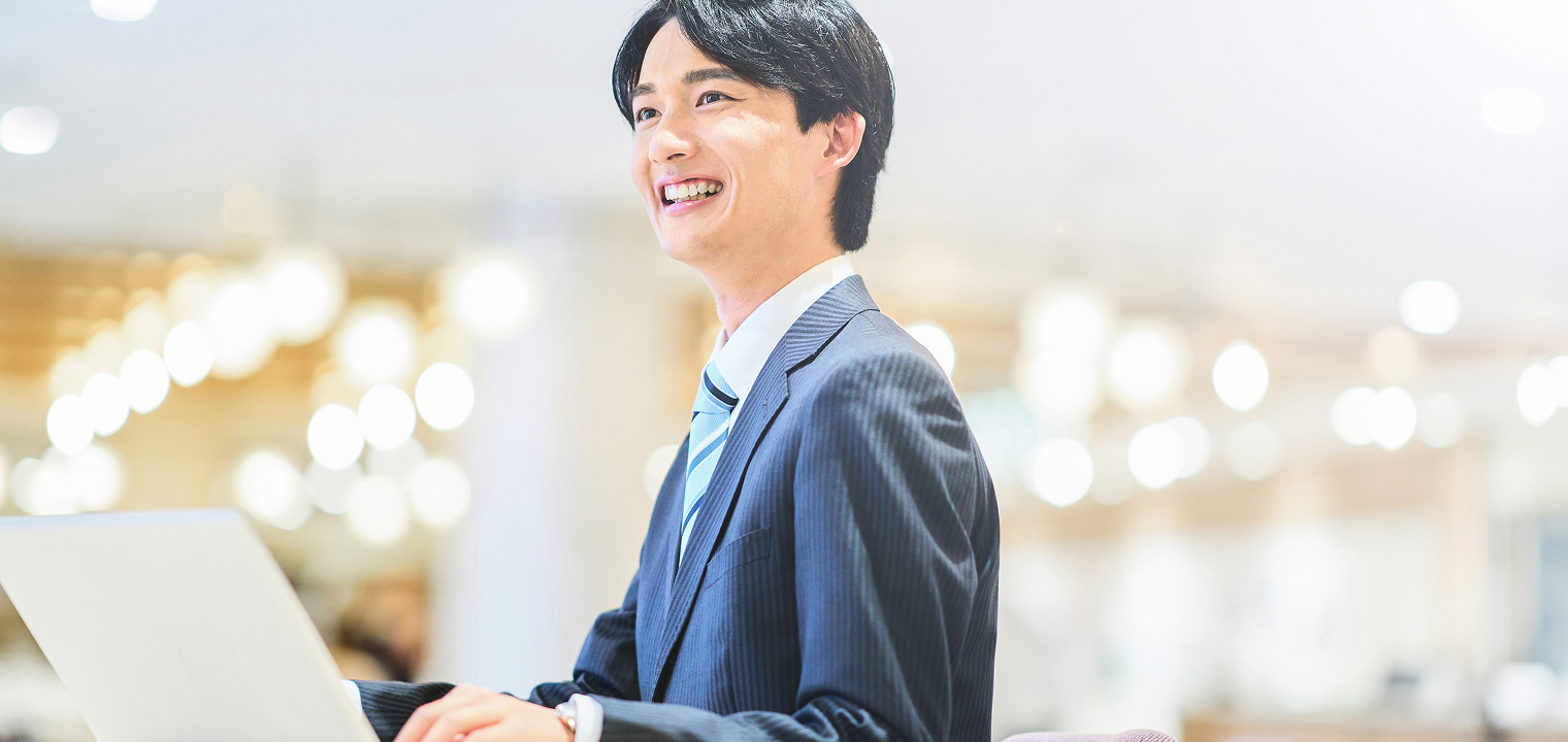 ノートパソコンで笑顔で作業する社員